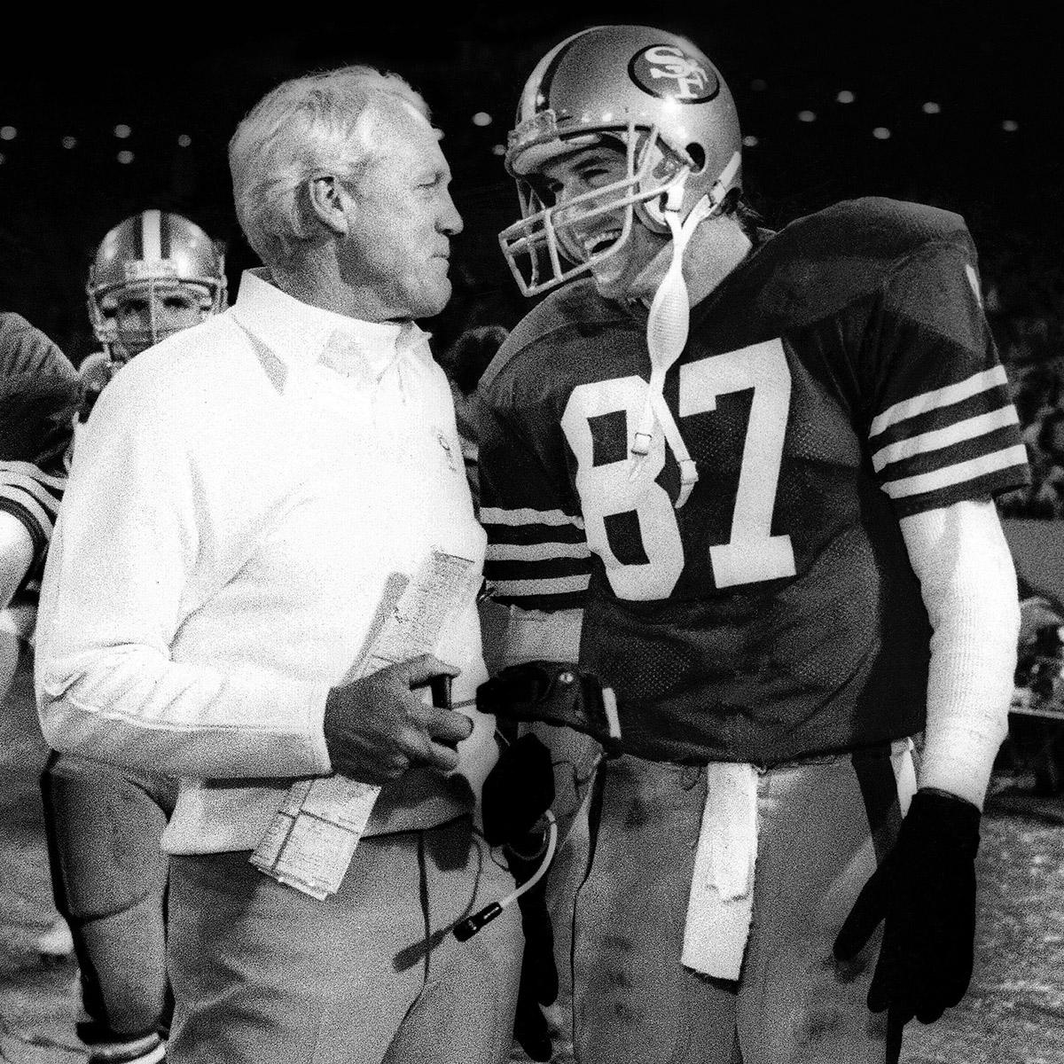 49ers head coach Bill Walsh speaks to wide receiver Dwight Clark during a game