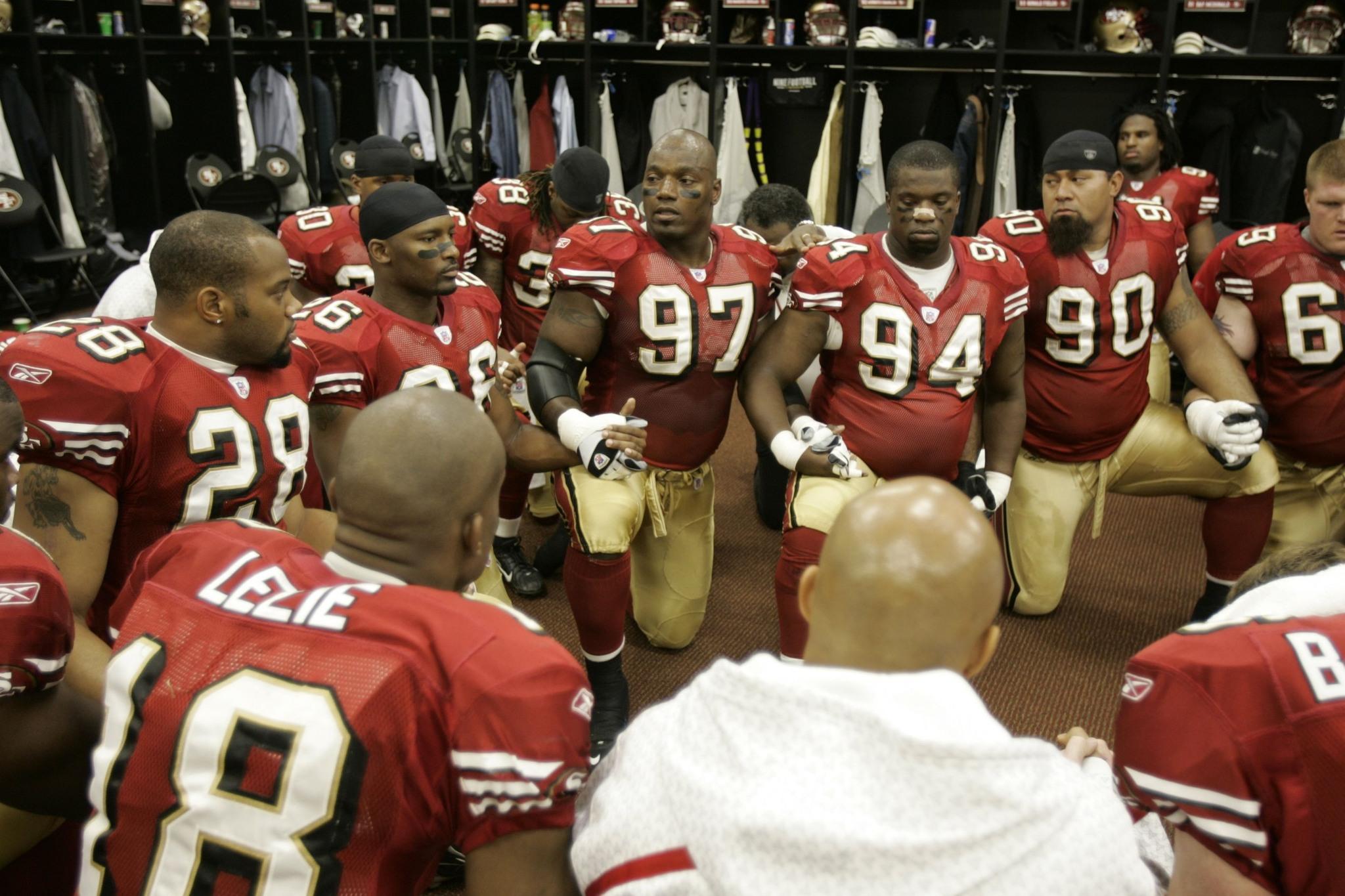49ers defensive lineman Bryant Young speaks to teammates in the locker room