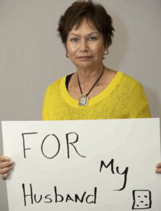 Liz Allardice, wife of Legacy Donor Robert Allardice, holds up a sign on why she's Racing to End CTE
