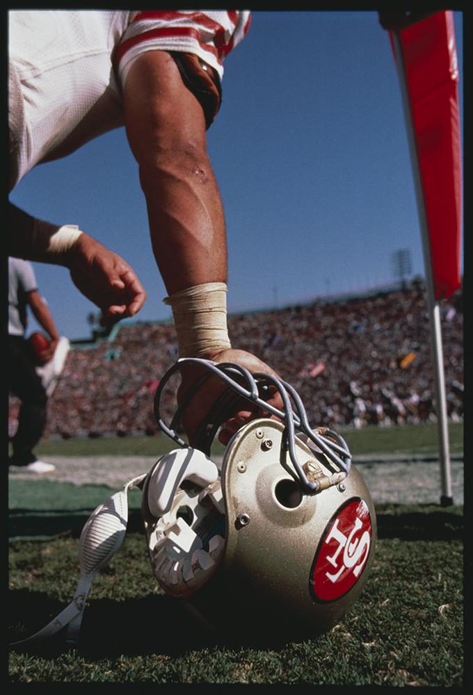 San Francisco 49ers player holds his helmet on the ground